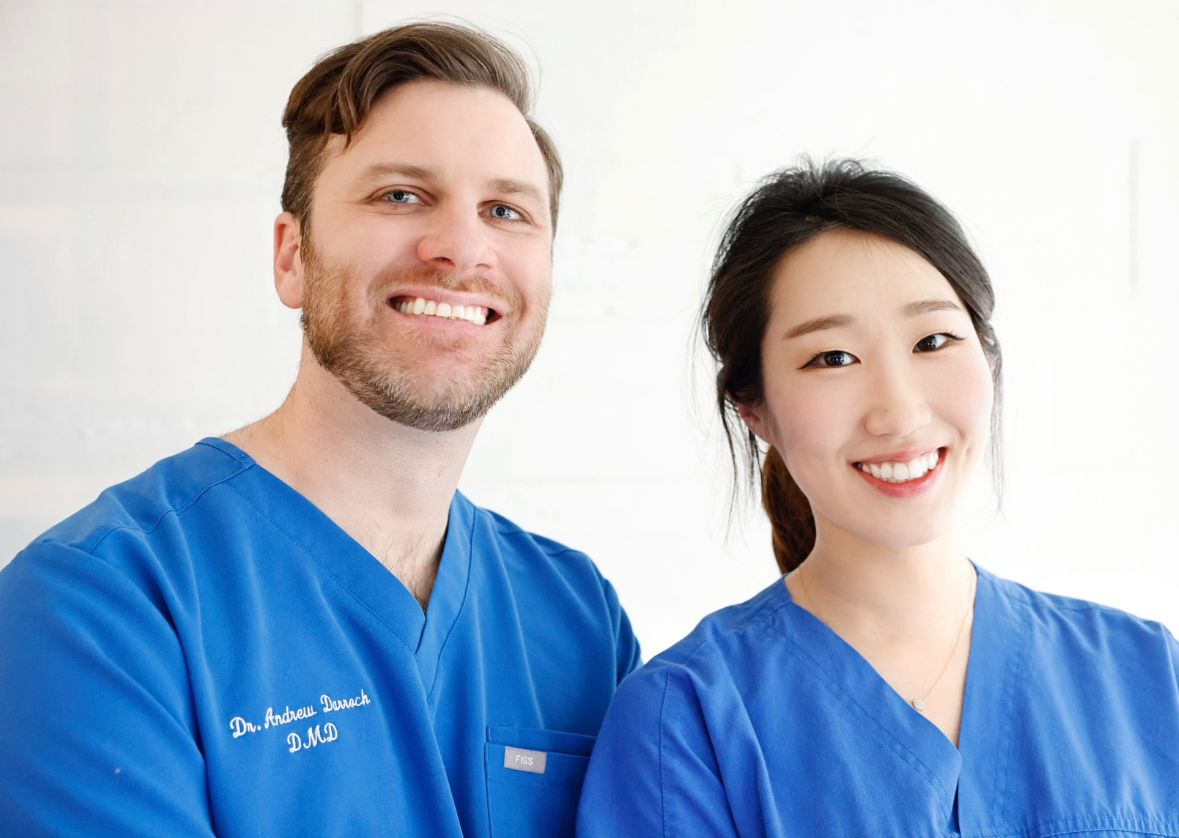 A man and a woman in blue scrubs posing for a photo.